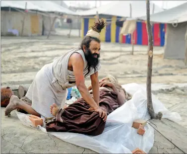  ??  ?? A sadhu massages his guru’s leg on the banks of the river Ganga in Allahabad on Saturday. AFP