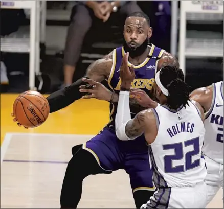  ?? Marcio Jose Sanchez Associated Press ?? LeBRON JAMES passes around Sacramento’s Richaun Holmes, back after missing 21 games in which the Lakers went 8-13.