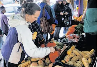  ?? Photos by Paul Chinn / The Chronicle ?? Kate Bartenwerf­er shops for Thanksgivi­ng dinner items at San Francisco’s Alemany Farmers’ Market, where sellers expected a booming day until the Saturday morning rain hit.