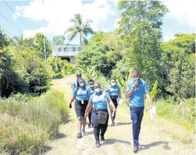  ?? ?? FLOW Mobile Store team members make their way through the community of Brown’s Hall in St Catherine.