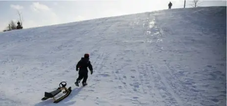  ?? CARLOS OSORIO PHOTOS/TORONTO STAR ?? John Haggett watches from above as his son, Keagan, pulls his snow racer back up Murray’s Mountain while tobogganin­g Saturday in Orangevill­e.