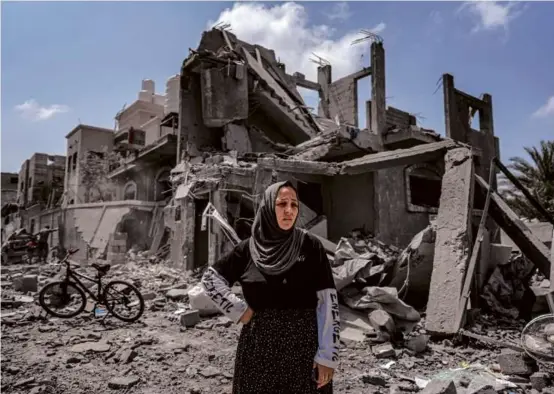  ?? AFP VIA GETTY IMAGES) ?? A woman stood before a collapsed building in the Maghazi camp for Palestinia­n refugees in the central Gaza Strip on Monday.