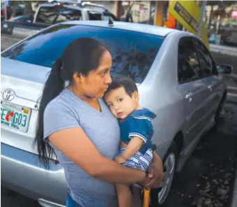  ?? AP PHOTO BY BRYNN ANDERSON ?? Buena Ventura Martin-Godinez, from Guatemala, holds her son, Pedro, as she waits for her brother to cross the street in Homestead, Fla., on Wednesday. She came to the U.S. to help her family and ended up having it torn apart instead. Martin carried her...