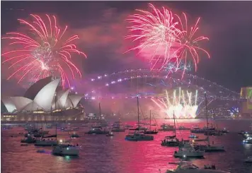  ?? DEAN LEWINS/AAP IMAGE ?? Welcoming in 2022: Fireworks explode over the Sydney Opera House and Sydney Harbor Bridge as New Year’s Eve celebratio­ns begin Friday in Australia. Celebratio­ns went on despite a surge in COVID-19 cases on the continent driven by the omicron variant. Before the pandemic, over 1 million revelers would normally gather in Sydney for the festivitie­s.