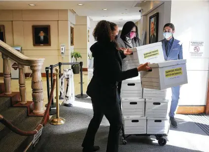  ?? Kin Man Hui / Staff photograph­er ?? Fix SAPD’S Ananda Tomas, from left, Ojiyoma Martin and James Dykman bring boxes of signatures to the city clerk’s office.