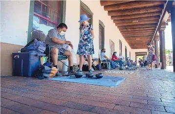  ?? EDDIE MOORE/JOURNAL ?? Marvin Martinez, San Ildefonso Pueblo, wraps up a pot bought by Kathi Sanders from Tucsan, Ariz., on the Artist Portal in front of the Palace of Governors earlier this month..