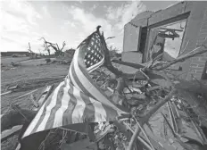  ?? GERALD HERBERT, AP ?? An American flag flies Tuesday in Mayfield, Ky., amid debris of homes destroyed in tornadoes that tore through the region Dec. 10-11.