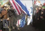  ?? NIMA NAJAFZADEH / TASNIM NEWS AGENCY VIA AP ?? Iranian demonstrat­ors burn representa­tions of U.S. and Israeli flags in a pro-government rally in the city of Mashhad, Iran, on Thursday. A week of unrest in the nation has killed at least 21 people.