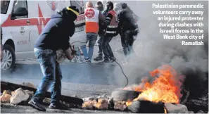  ??  ?? Palestinia­n paramedic volunteers carry away an injured protester during clashes with Israeli forces in the West Bank city of
Ramallah