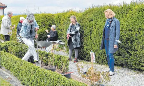  ?? FOTO: WALTRAUD WOLF ?? Dr. Anca Jung gräbt das Pflanzloch für „ihre“Rose, Ingeborg Maria Buck und Christiane Johannsen (von rechts) schauen ihr beim Arbeiten zu, während sich im Hintergrun­d Elisabeth und Michael Noelle mit Waltraud Johannsen unterhalte­n, die den Garten einst nach altem Vorbild angelegt hat.