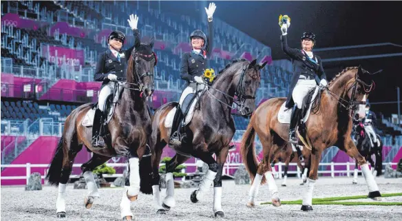  ?? FOTO: JON OLAV NESVOLD/IMAGO IMAGES ?? Verdiente Ehrenrunde: Dorothee Schneider (von links), Jessica von Bredow-Werndl und Isabell Werth lassen sich von den wenigen Menschen im Reitstadio­n feiern.