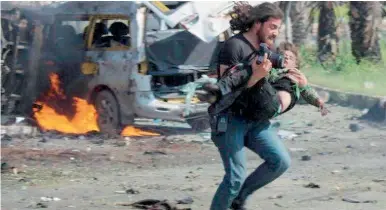  ??  ?? سوري يحمل طفال مصابا في موقع التفجير االنتحاري الذي استهدف حافالت تقل مهجري الفوعة وكفريا أمس. (رويترز)