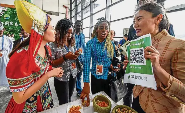  ?? Daily — China ?? Internatio­nal market: Foreign visitors to an expo in Nanning indicate interest in forestry by-products and pay for them using WeChat Pay.