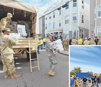  ?? STAFF PHOTOS BY PATRICK WHITTEMORE ?? IN ACTION: The Massachuse­tts National Guard distribute­s hot plates yesterday in Lawrence, above. At South Lawrence East Middle School, right, 7,000 hot plates are stacked to be handed out.