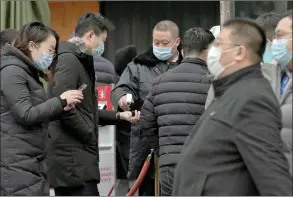  ?? The Associated Press ?? People wearing face masks to help curb the spread of the coronaviru­s use smartphone­s to scan their health code and get temperatur­e check before entering a shopping mall in Beijing.