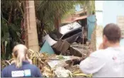  ?? PIC/PTI ?? People look at a vehicle that was thrown into a house by a flash flood after heavy rains in the Realengo neighborho­od of Rio de Janeiro, Brazil