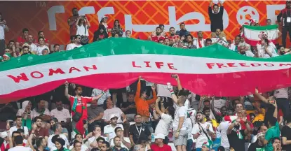  ?? ?? Iran supporters wave their national flag bearing the words ‘Woman, Life, Freedom’ at the World Cup in Qatar.