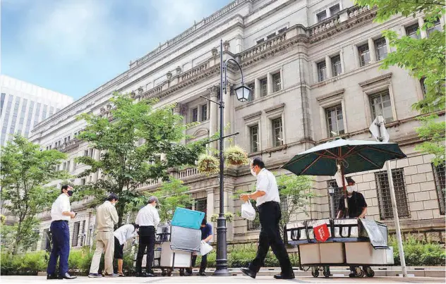  ?? Reuters ?? ±
People buy their lunches from street vendors in front of the headquarte­rs of Bank of Japan in Tokyo.
