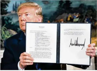  ?? DOUG MILLS / NEW YORK TIMES ?? President Donald Trump displays a presidenti­al memorandum that withdraws the United States from the Iran nuclear deal after signing the document Tuesday in the White House Diplomatic Room. The action makes good on Trump’s campaign pledge to undo the...