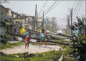  ?? The Associated Press ?? STORM DAMAGE: Residents walk near downed power lines felled by Hurricane Irma on Saturday in Caibarien, Cuba. There were no reports of deaths or injuries after heavy rain and winds from Irma lashed northeaste­rn Cuba. Seawater surged three blocks inland...