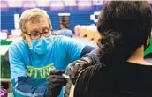  ?? KRISTIAN CARREON ?? Retired anesthesio­logist Randolph Hastings administer­s a Moderna vaccine dose to Anh Tran at the Cal State San Marcos Clarke Field House this week.