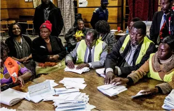  ??  ?? Electoral workers tally presidenti­al candidates ballots during counting operations for Zimbabwe’s general election at the David Livingston Primary school in central Harare. — AFP photo