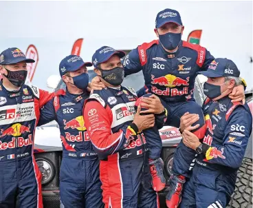  ?? (AFP) ?? French driver Stephane Peterhanse­l is lifted by Nasser al Attiyah and Carlos Sainz (right) following his victory in the Dakar Rally on Friday