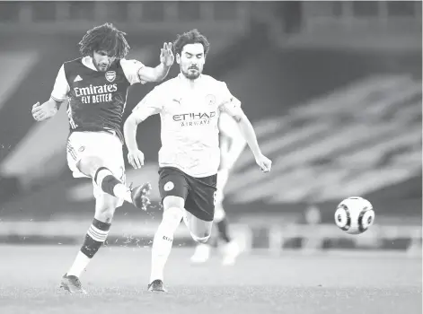  ?? - AFP photo ?? Arsenal's Egyptian midfielder Mohamed Elneny (L) has an unsuccessf­ul shot under pressure from Manchester City's German midfielder Ilkay Gundogan (R) during the football match at the Emirates Stadium in London on February 21, 2021.