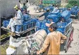  ?? AFP ?? Vendors fill cans with drinking water from a water supply plant for selling during a heatwave in the city of Jacobabad.