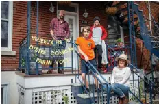  ?? Montreal.—AFP photos ?? Guy Bourbonnai­s (left), Valerie Harbec (right) and their sons Louis and Charles Bourbonnai­s, pose with their banner “Happy to be confined with you” by artist Patsy Van Roos in