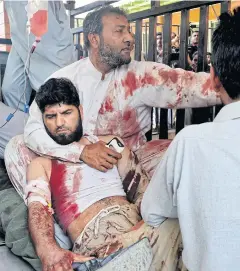  ?? AP ?? Volunteers carry an injured man to a hospital in Peshawar, Pakistan, following a suicide bombing Jamaat-ul-Ahrar said it conducted in March.