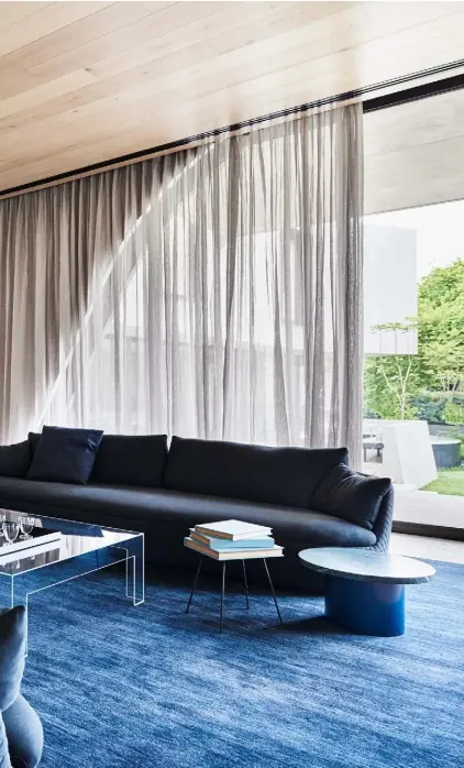  ??  ?? Living room Facing out to the garden, this is the property’s formal reception area. Elegant touches such as the brass-edged mirrored glass wall and fringed poufs from Gubi add a shot of glamour. A pair of deep-blue ‘Bart’ sofas by Dutch designer Bart Schilder for Moooi sit on a similarly coloured rug from the ‘Agra’ collection by Armadillo & Co. The glass coffee table is the ‘Atlantis’ by Lorenzo Arosio for Glas Italia