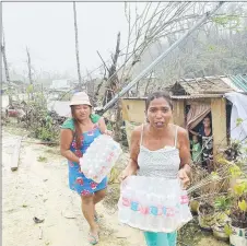  ?? ?? Residents carry bottled water given as aid from a non-government­al organisati­on in Burgos town, Siargao island, weeks after super Typhoon Rai devastated the island. — AFP photo