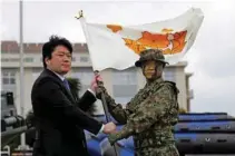  ?? - Reuters/Issei Kato ?? CEREMONY: Japan’s State Minister of Defence Tomohiro Yamamoto, left, gives a brigade flag to Maj. Gen. Shinichi Aoki, commander of Japanese Ground Self-Defence Force (JGSDF)’s Amphibious Rapid Deployment Brigade, Japan’s first marine unit since World...