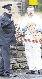  ?? PHOTOS: DAMIEN EAGERS ?? Garda probe: A forensic investigat­or (far left) examines the damaged window of the hotel. Left: Supt Kevin English speaks to a crime scene investigat­or outside the hotel.