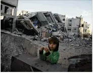  ?? KHALIL HAMRA / ASSOCIATED PRESS ?? A Palestinia­n child looks out from the rubble of Hamas’ Al-Aqsa TV station, which was hit by an Israeli airstrike Monday in Gaza City.