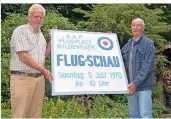  ?? FOTO: D. BEINEKE ?? Artur Tellers (l.) und Hans Esser mit dem Originalsc­hild, mit dem vor 50 Jahren für die große Flugschau in Wildenrath geworben wurde.