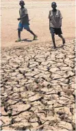  ?? FOTO: DPA ?? Zwei Jungen laufen über von der Dürre aufgebroch­ene Erde: Der Klimawande­l gefährdet auch die deutsche Wirtschaft.
