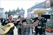  ?? MARCO UGARTE/THE ASSOCIATED PRESS ?? A man wearing a ‘Lucha Libre’ wrestling mask poses for a selfie with traditiona­l mariachi musicians Thursday at the Hermanos Rodriguez racetrack in Mexico City. After an earthquake in Septebmer, the track itself became a staging area for relief...