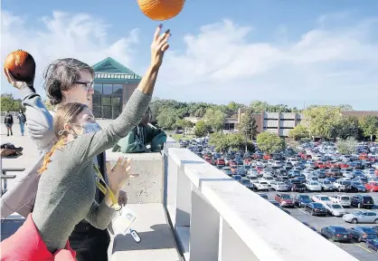  ?? JOHN SMIERCIAK/POST-TRIBUNE ?? Freshman Laurain Matson, left, and sophomore John Tomczak throw pumpkins during a pumpkin toss from the parking garage at Purdue Northwest. The Office of Student Life put on the event Tuesday as a way for students to take a study break.