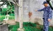  ??  ?? A prison officer points to a wall with blood stains belonging to a prison guard who was killed after gunmen stormed the prison