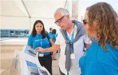  ?? Courtesy: WFP ?? Peter Casier (centre) and WFP staff members flip through the FITTEST 20th anniversar­y photobook.