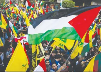  ?? AP PHOTO ?? Protesters in a southern suburb of Beirut, Lebanon, wave Palestinia­n, Lebanese and Hezbollah flags during a march in a street in response to a call by Hezbollah leader Sheikh Hassan Nasrallah to protest U.S. President Donald Trump’s decision to...