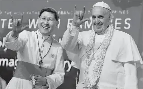  ?? L’OSSERVATOR­E ROMANO ?? Manila Archbishop Luis Antonio Tagle and Pope Francis salute the crowd with the popular hand sign for during a meeting with families at the Mall of Asia arena in Manila.