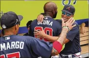  ??  ?? New Atlanta Braves member Marcell Ozuna (center) hugs Martin Prado in the dugout before a spring training game against the Tampa Bay Rays on March 3 in Venice, Fla.