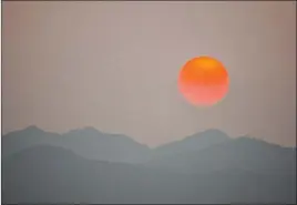  ?? Ellen Schmidt Las Vegas Review-journal @ellenkschm­idttt ?? The sun, clouded by smoke from fires in California, sets Monday behind Spring Mountains National Recreation Area. Monday’s high was 106; Tuesday is expected to reach only 85.
