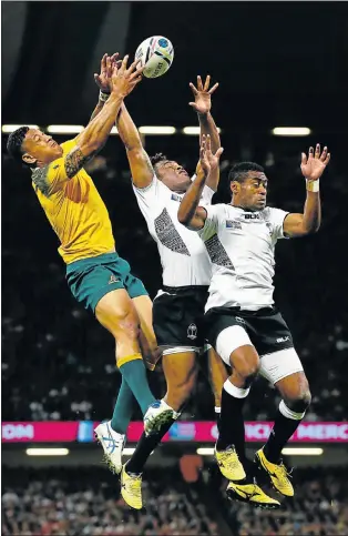  ?? Picture: GETTY IMAGES ?? FULL STRETCH: Australia’s Israel Folau jumps for the ball with Fiji’s Metuisela Talebula and Asaeli Tikoirotum­a during their World Cup Pool A match at the Millennium Stadium in Cardiff yesterday