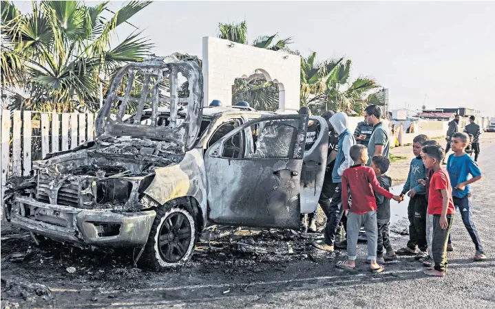  ?? ?? People gather around an NGO car following a missile strike, after which British, Polish and Australian passports, below, were found; another car, bottom, was hit on its aid badge