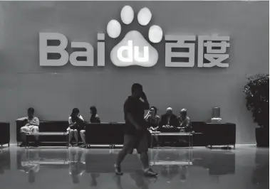  ?? REUTERS ?? An employee uses his mobile phone as he walks past the company logo of Baidu at its headquarte­rs in Beijing.