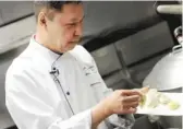  ??  ?? Executive chef Arun Sampanthav­ivat prepares food in the kitchen of Arun’s Thai Restaurant.